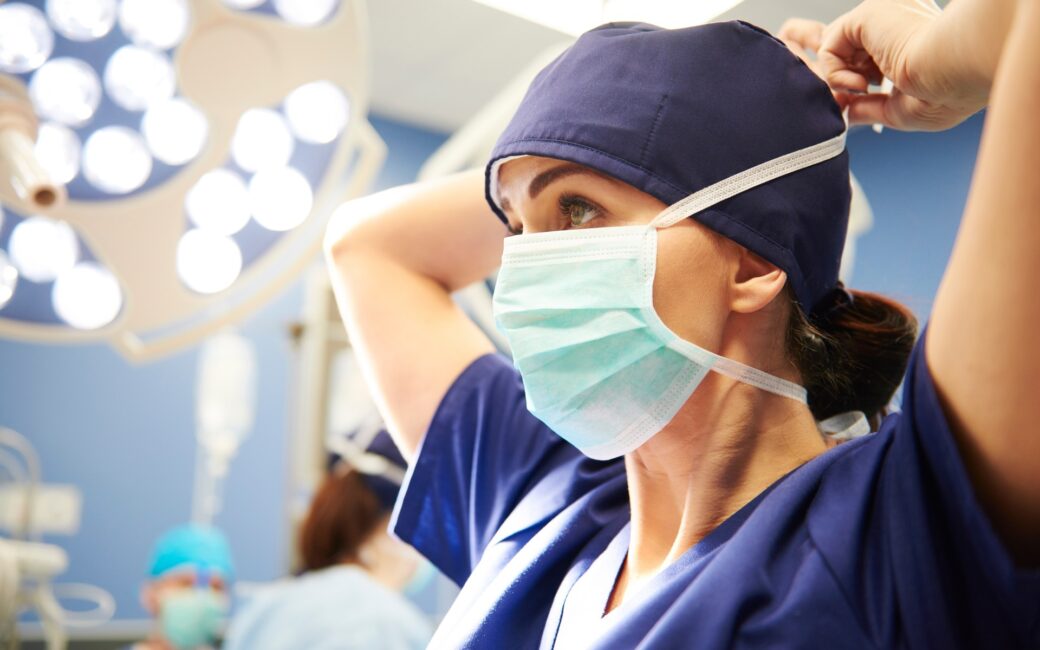 Nurse wearing face mask stretching and getting ready to help implement a medical procedure