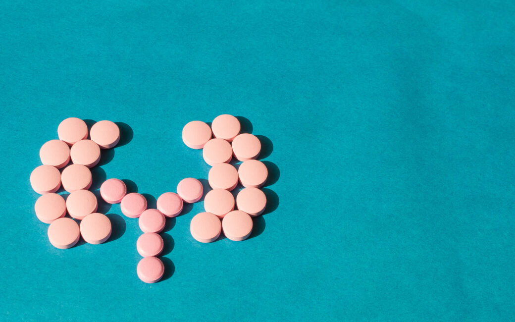 pink pills in the shame of kidneys on a blue background