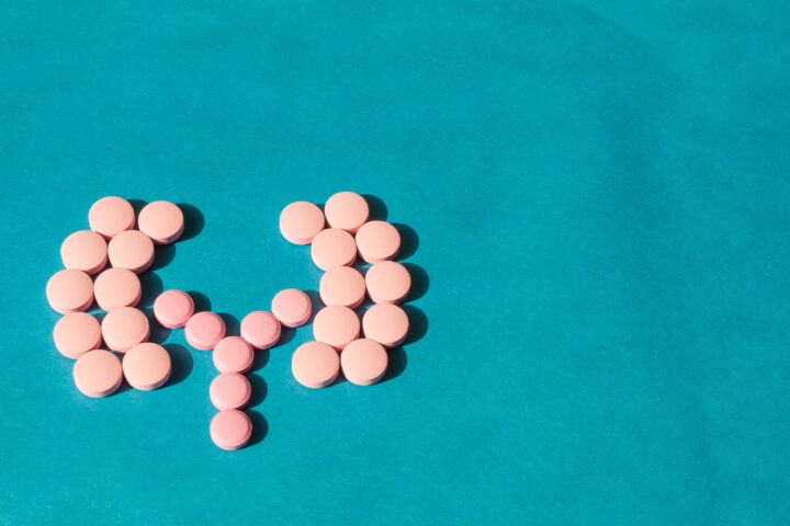 pink pills in the shame of kidneys on a blue background